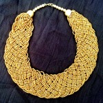 Golden strands of beads braided into a wide collared necklace