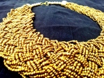Golden strands of beads braided into a wide collared necklace